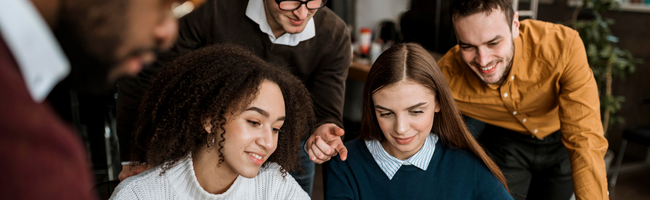 Equipe de colaboradores reunida no ambiente de trabalho, compartilhando ideias e colaborando em uma atividade em grupo.
