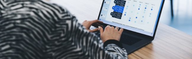 Profissional utilizando notebook com plataforma digital de gestão, exibindo dados e indicadores que auxiliam na automação de processos e na tomada de decisões do RH.