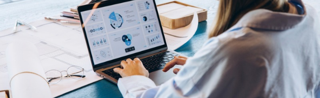Profissional utilizando tecnologia para RH em notebook com dashboard de indicadores, gráficos e dados para apoiar a gestão de pessoas.